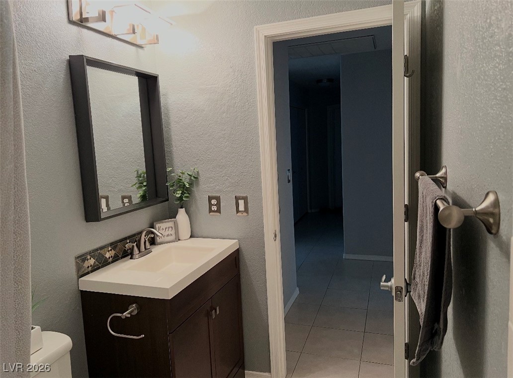 881 Brass Ring Road Las Vegas, NV 89123 - Photo 8 of 13 Half bath featuring vanity, a textured wall, and light tile patterned floors