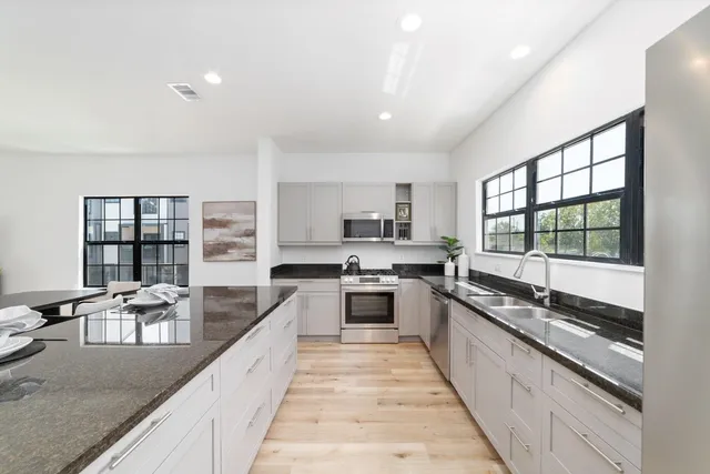 a large kitchen with granite countertop lots of counter space a sink and stainless steel appliances