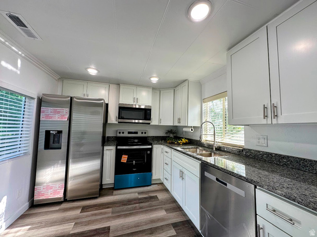 629 North 100 East Logan, UT 84321 - Photo 5 of 11 Modern kitchen featuring white cabinetry, dark granite countertops, and stainless steel appliances including a refrigerator, microwave, range, and dishwasher