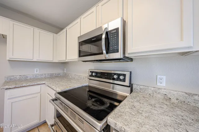 a kitchen with stainless steel appliances granite countertop white cabinets and stove