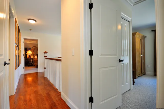 a view of a hallway with wooden floor and a living room