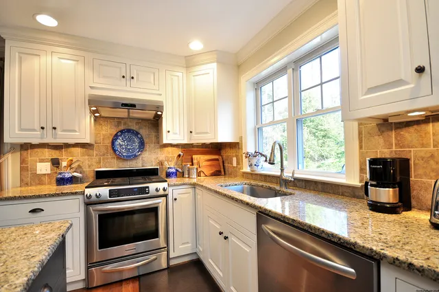 a kitchen with granite countertop cabinets stainless steel appliances a sink and a window