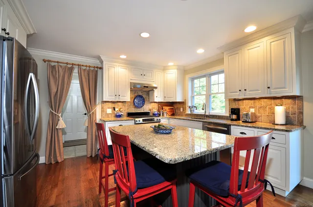 a kitchen with a refrigerator a stove a sink dishwasher and a dining table with wooden cabinet