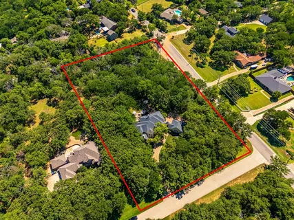 an aerial view of residential house with outdoor space and trees all around