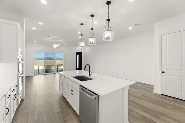 a kitchen with stainless steel appliances a stove a sink a center island and wooden floor