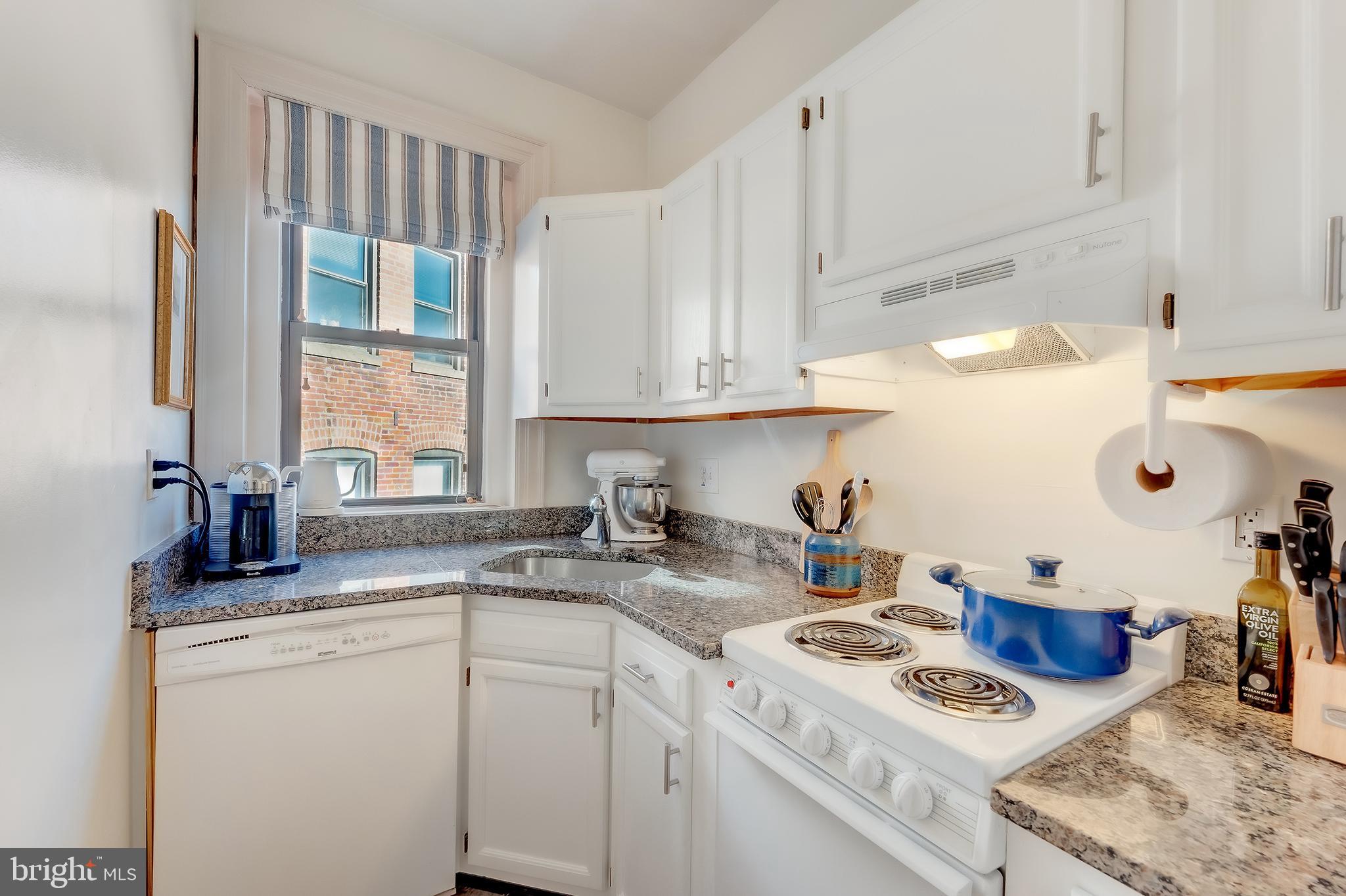 1918 18th Street Northwest, Unit 42 Washington, DC 20009 - Photo 10 of 22 a kitchen with kitchen island granite countertop a sink a stove and cabinets