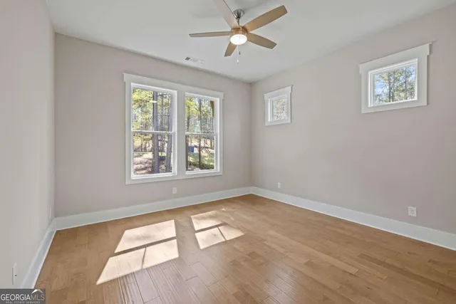 a view of empty room with wooden floor and fan