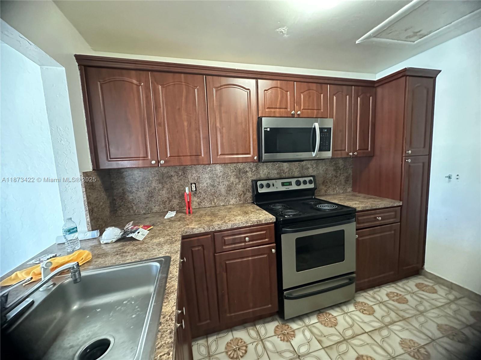 a kitchen with granite countertop a stove top oven microwave and cabinets