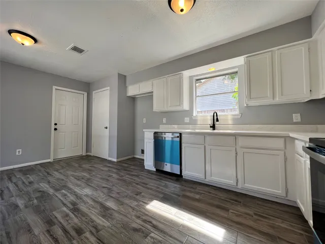 a kitchen with a sink cabinets and wooden floor