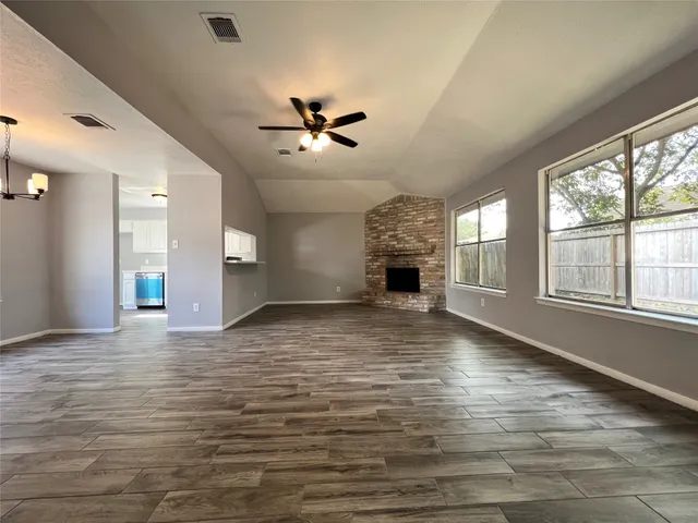 a view of empty room with wooden floor and fan