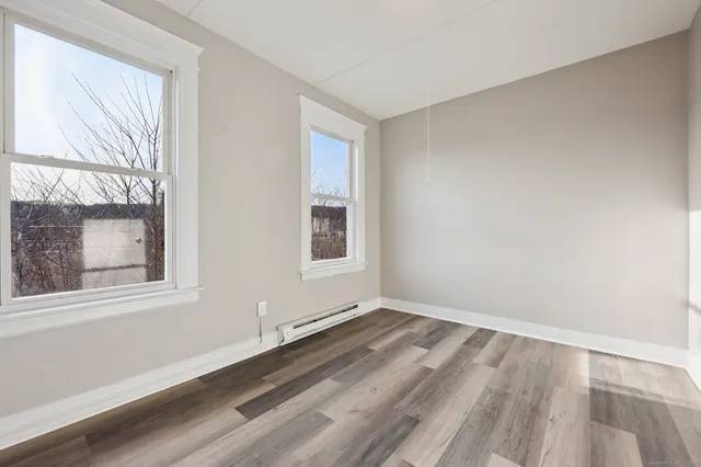a view of an empty room with wooden floor and a window