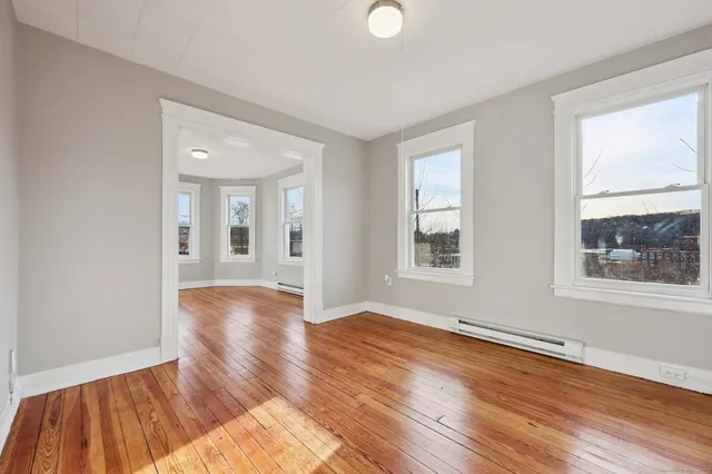 a view of an empty room with wooden floor and a window