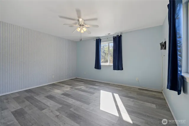 an empty room with wooden floor and fan
