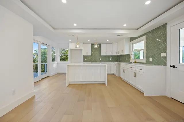 a large kitchen with granite countertop a white stove top oven and white cabinets
