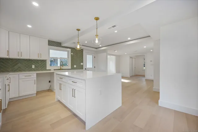 a view of a kitchen center island with stainless steel appliances granite countertop furniture and a chandelier