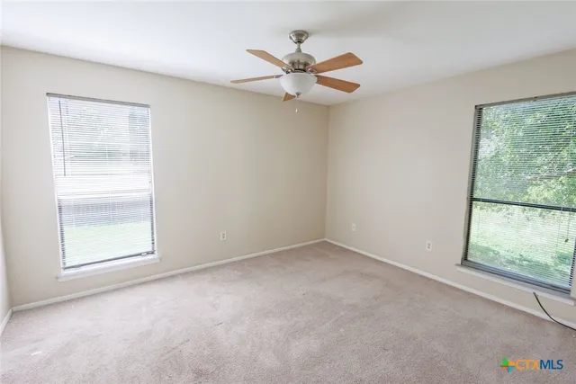 an empty room with a window and a fan