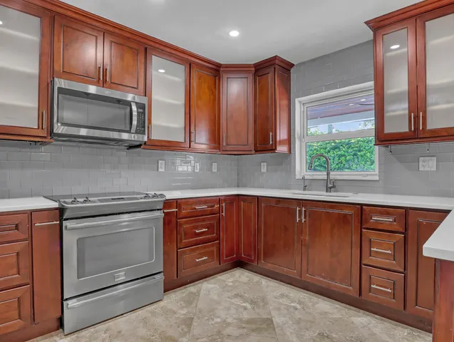 a kitchen with stainless steel appliances granite countertop wooden cabinets a stove a sink and a microwave