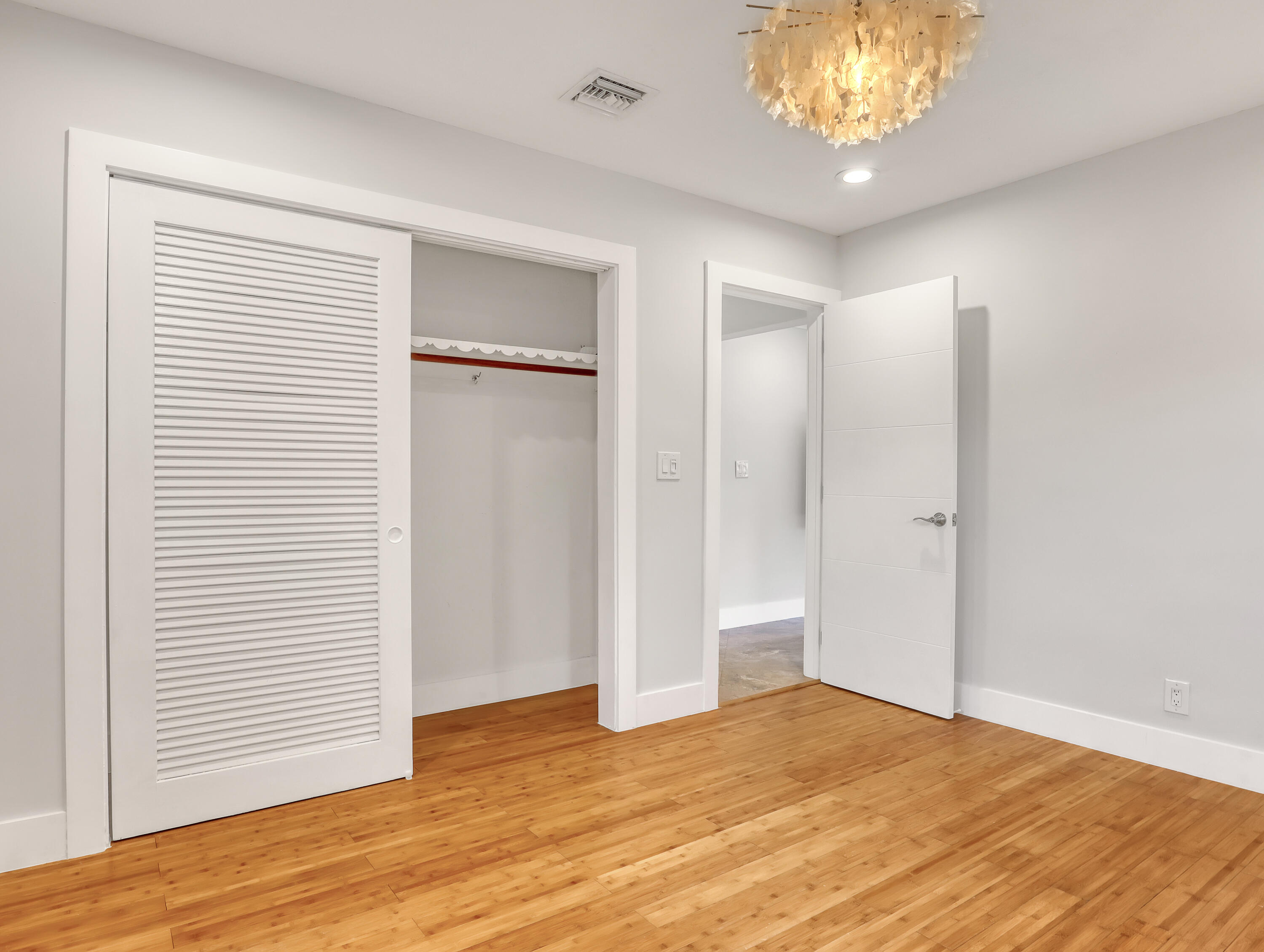 1298 Northwest 4th Street Boca Raton, FL 33486 - Photo 27 of 36 a view of an empty room with wooden floor and a chandelier