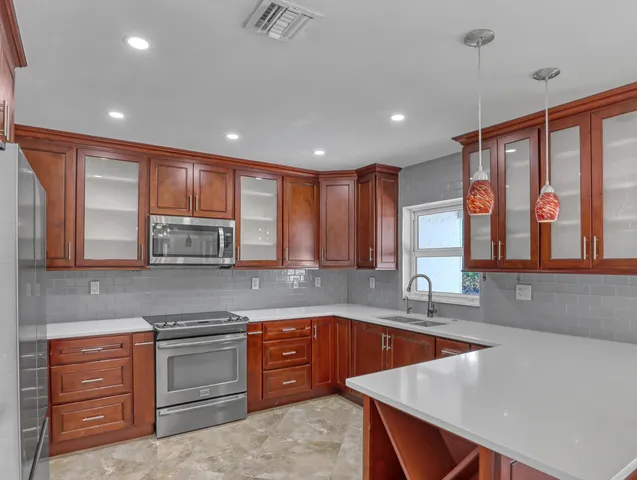 a kitchen with stainless steel appliances granite countertop a sink a stove and a wooden cabinets