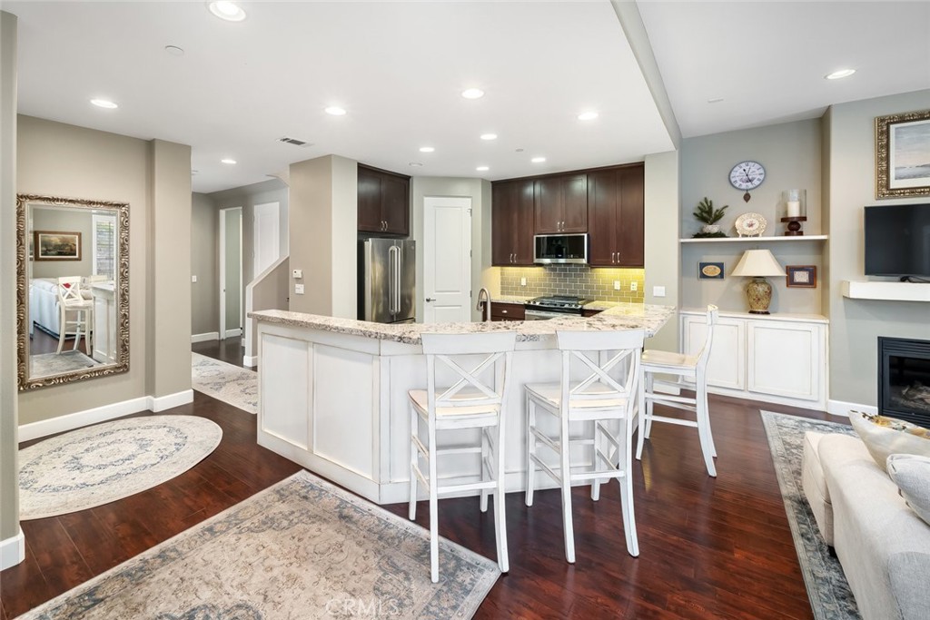 1187 Swallowtail Way Nipomo, CA 93444 - Photo 9 of 59 a kitchen with stainless steel appliances kitchen island granite countertop a stove a refrigerator and a dining table with wooden floor