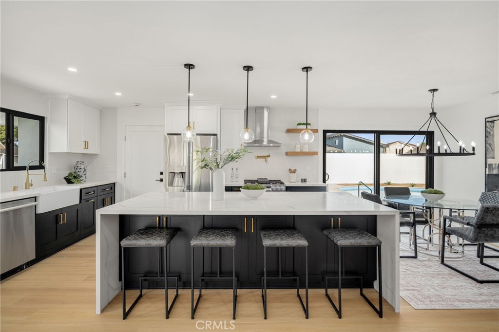 6072 Navajo Road Westminster, CA 92683 - Photo 6 of 26 a kitchen with stainless steel appliances kitchen island granite countertop a table chairs in it and white cabinets