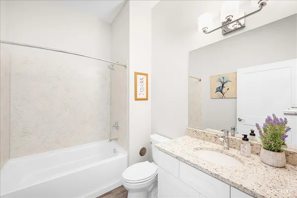 a bathroom with a granite countertop sink a toilet a mirror and shower