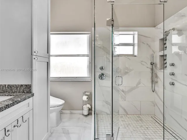 a bathroom with a granite countertop sink a toilet and shower