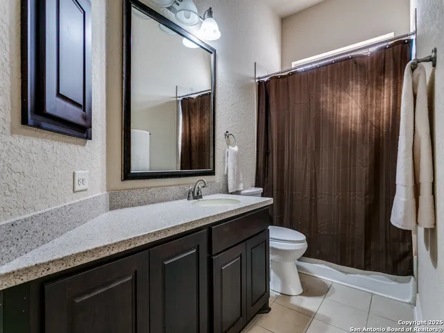 a bathroom with a granite countertop sink toilet and mirror