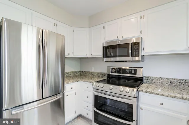 a kitchen with granite countertop white cabinets and stainless steel appliances