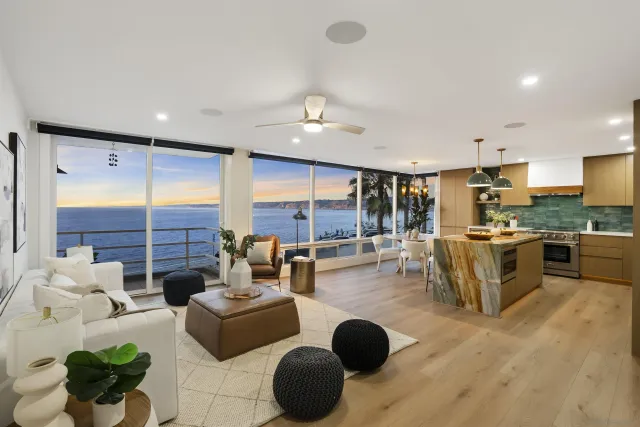 a living room with couches and kitchen view with wooden floor