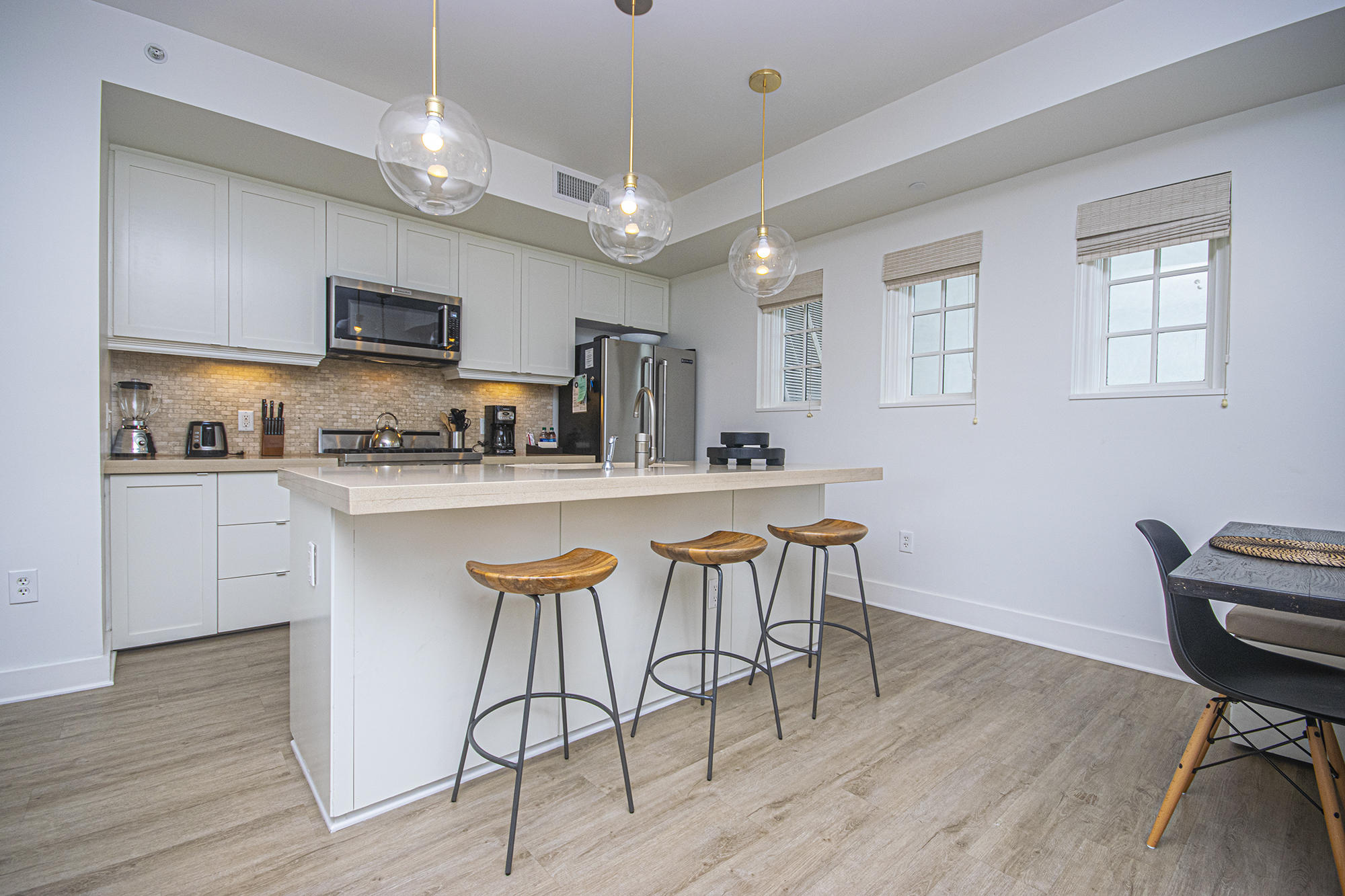 136 Georgetown Avenue, Unit 2E1 Rosemary Beach, FL 32461 - Photo 28 of 49 a kitchen with stainless steel appliances kitchen island granite countertop a sink a stove a refrigerator cabinets and dining table with wooden floor
