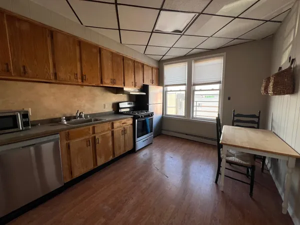 a kitchen with stainless steel appliances granite countertop a stove a sink dishwasher and microwave with wooden floor