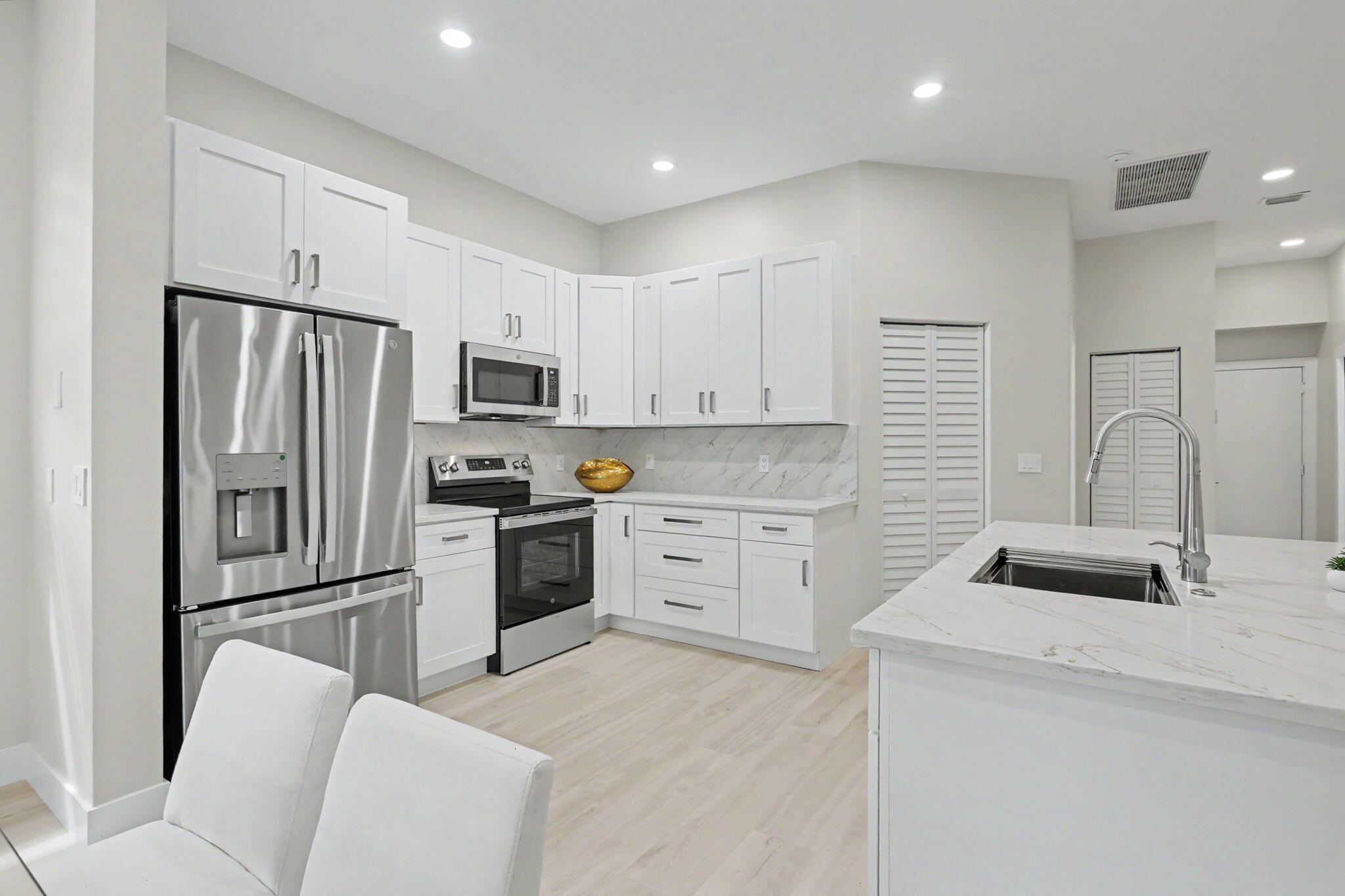 7832 Rockford Road Boynton Beach, FL 33472 - Photo 11 of 40 a kitchen with white cabinets and stainless steel appliances