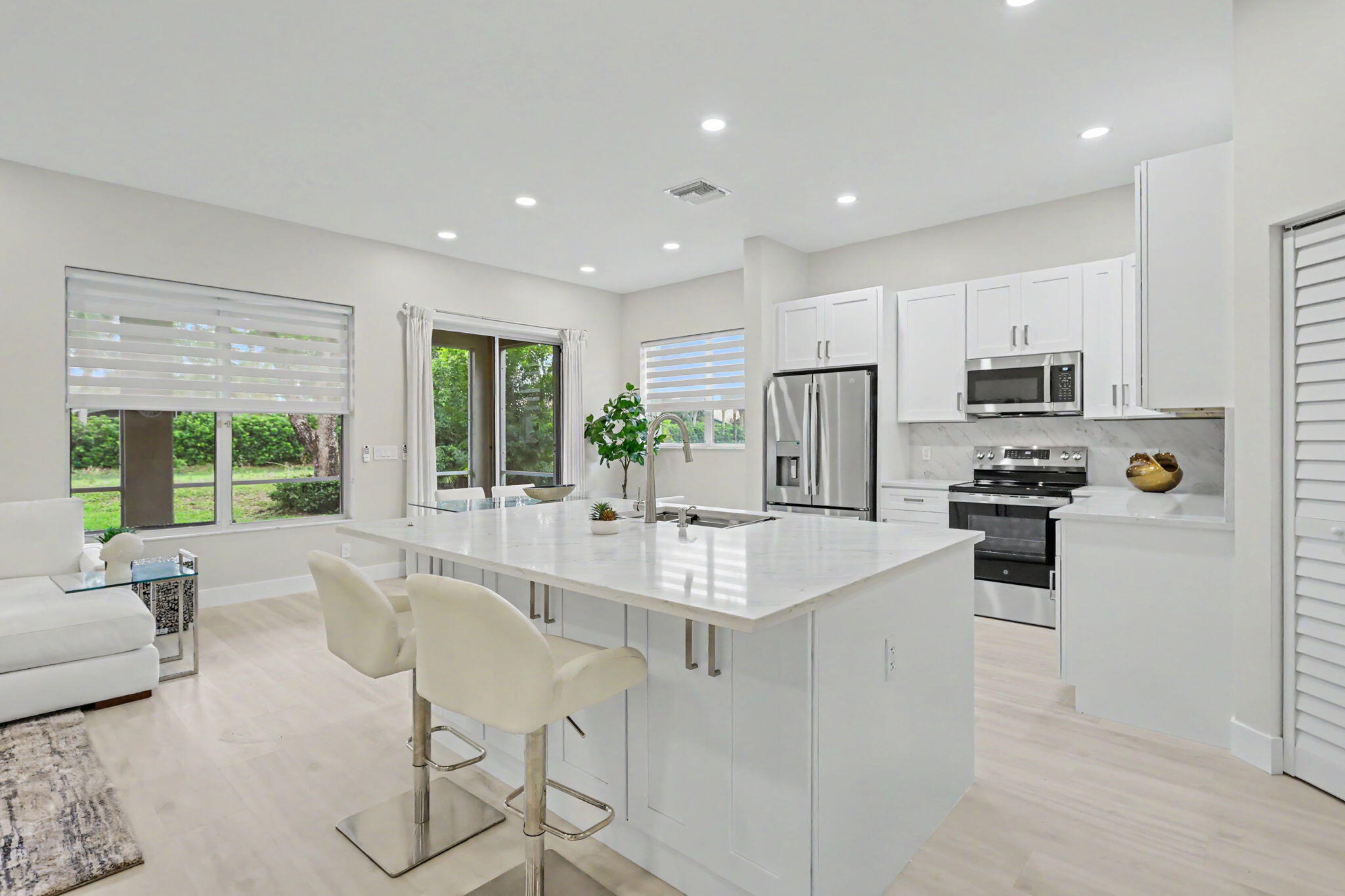 7832 Rockford Road Boynton Beach, FL 33472 - Photo 6 of 40 a kitchen with stainless steel appliances granite countertop a stove top oven a sink dishwasher a dining table and chairs with wooden floor