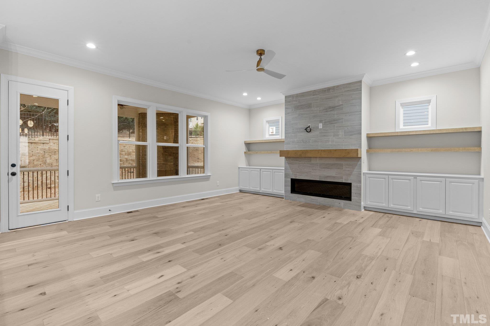 9321 Field Maple Court Raleigh, NC 27613 - Photo 16 of 44 an empty room with wooden floor fireplace and windows