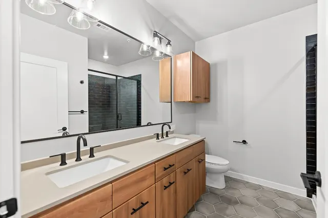 a bathroom with a sink double vanity granite and a toilet