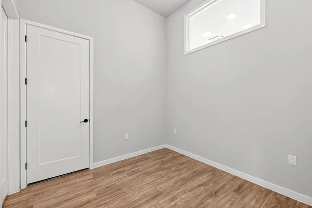 a view of an empty room with wooden floor and closet