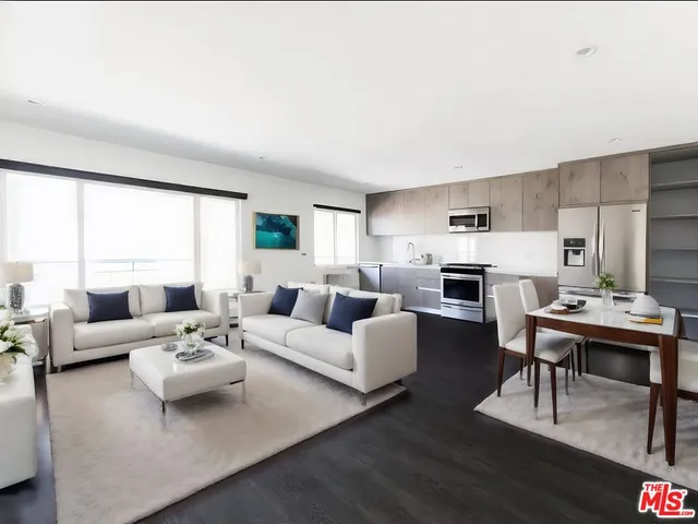 a living room with furniture white walls and kitchen view
