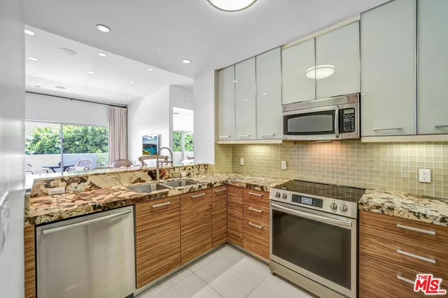 a kitchen with stainless steel appliances granite countertop a stove top oven a sink a dining table and chairs