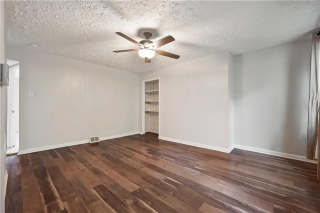 an empty room with wooden floor fan and windows