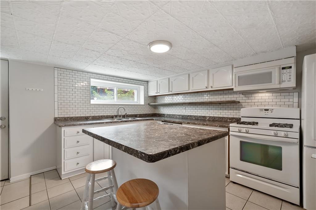22 Eleanor Street Pittsburgh, PA 15203 - Photo 7 of 36 a kitchen with granite countertop a stove a sink and a microwave
