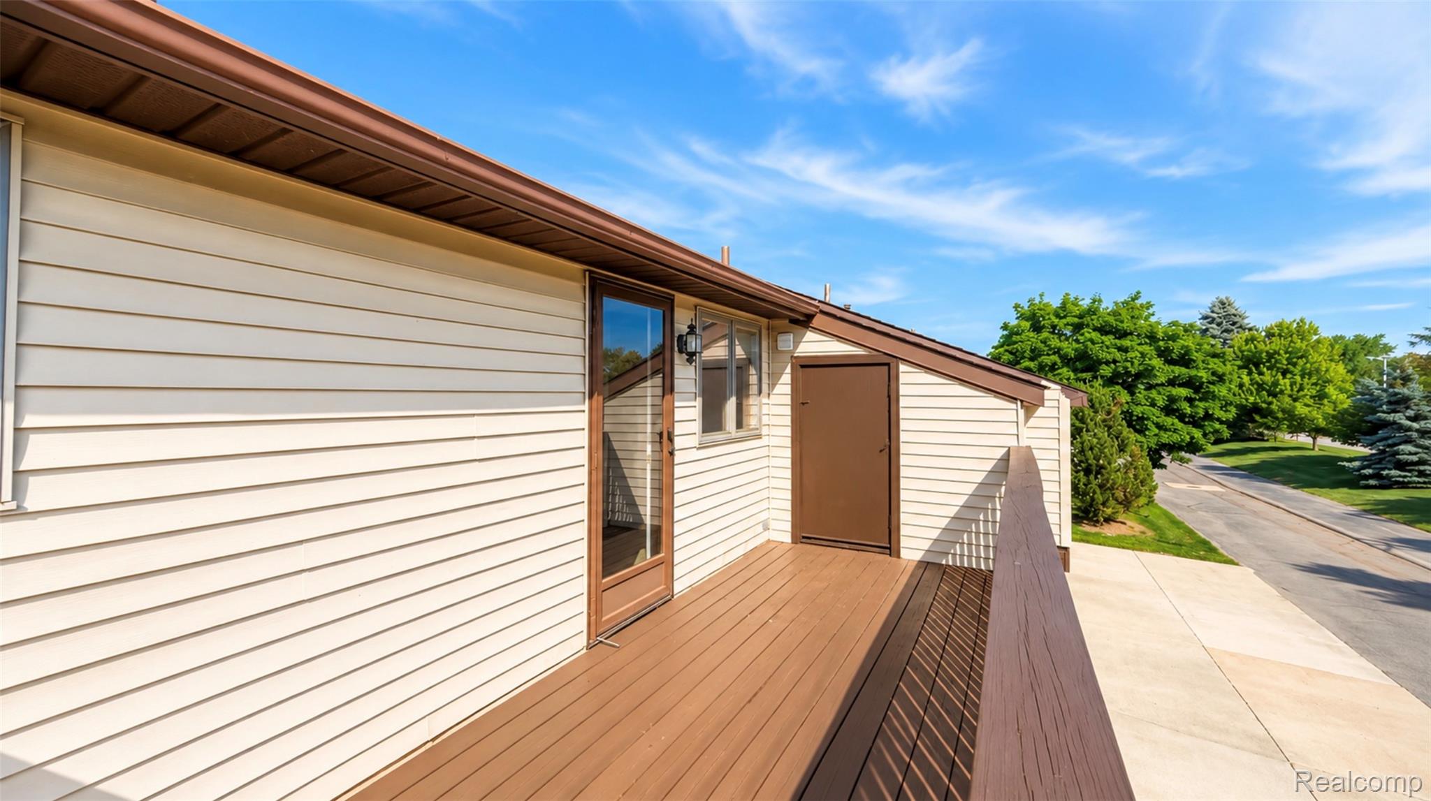 2232 London Bridge Drive, Unit 42 Rochester, MI 48307 - Photo 11 of 20 Exterior deck featuring composite wood-finish flooring, a glass-paneled door, and a brown railing