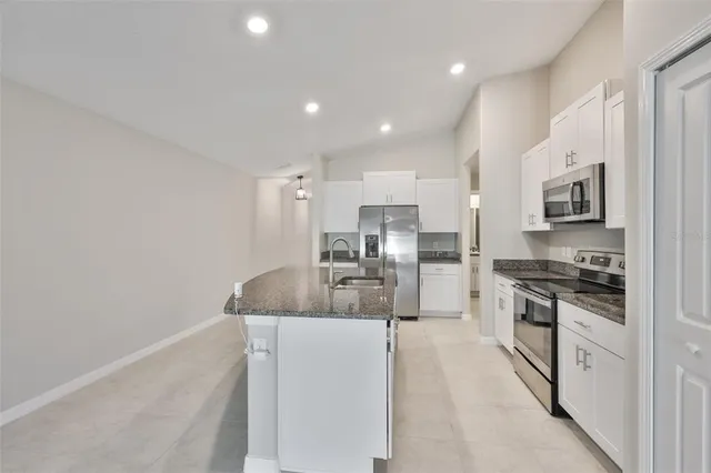 a kitchen with stainless steel appliances kitchen island granite countertop a refrigerator and a sink