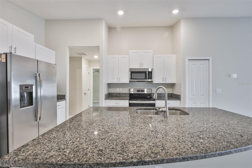 31867 Barrel Wave Way Wesley Chapel, FL 33545 - Photo 16 of 45 a kitchen with stainless steel appliances kitchen island granite countertop a refrigerator and a sink