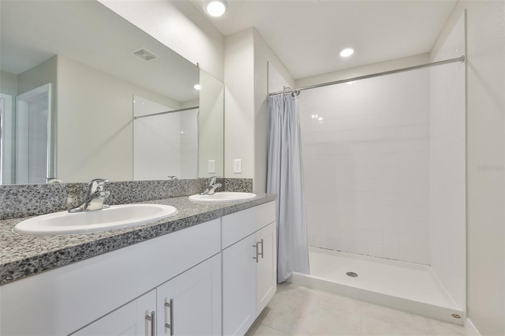 31867 Barrel Wave Way Wesley Chapel, FL 33545 - Photo 22 of 45 a bathroom with a granite countertop sink a mirror and a shower