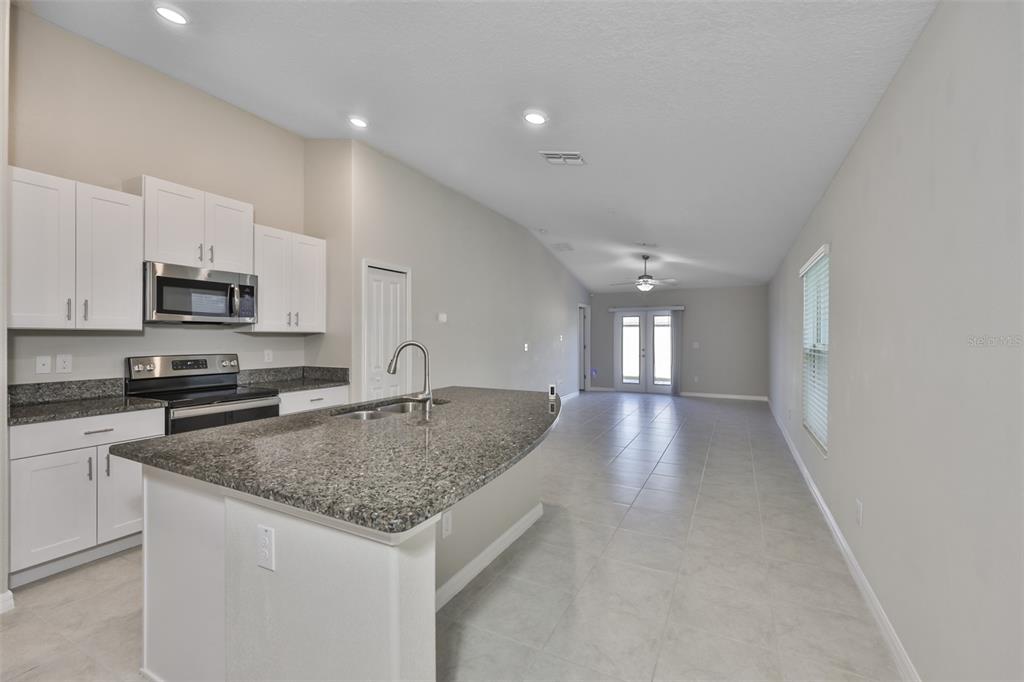 31867 Barrel Wave Way Wesley Chapel, FL 33545 - Photo 9 of 45 a view of a kitchen island a sink dishwasher a stove with wooden cabinets