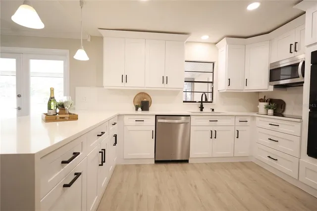 a kitchen with stainless steel appliances kitchen island granite countertop a table chairs sink and cabinets