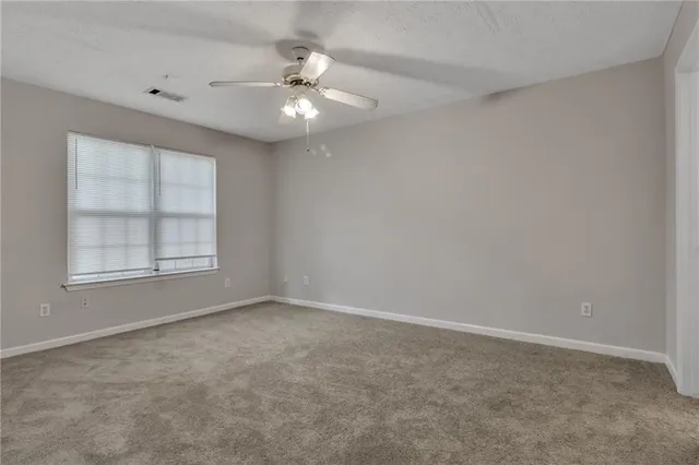 an empty room with windows and chandelier fan