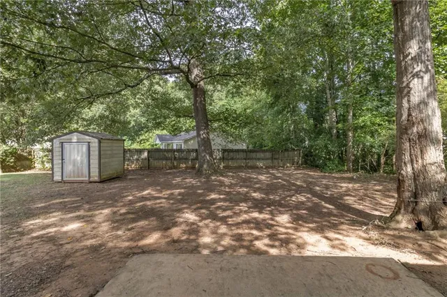 a backyard of a house with large trees and a barn