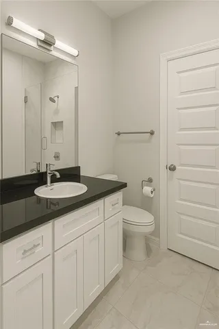 a bathroom with a granite countertop sink toilet a mirror and shower
